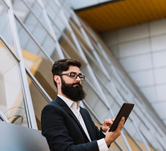 young-beard-businessman-leaning-wall-looking-smartphone_23-2147941661